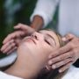 Reiki therapist holding hands on both sides of patient head and transfer energy. Beautiful and peaceful teenage girl lying with her eyes closed. Alternative therapy concept.